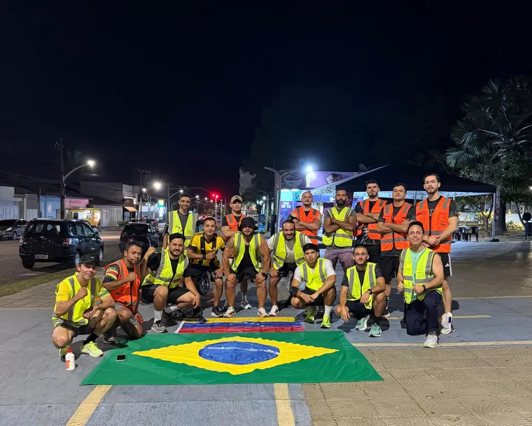 Staff e batedores dos Miranteiros reunidos à noite na praça com coletes refletivos e bandeiras